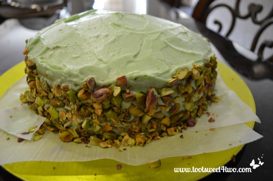 Smushing pistachios around the cake
