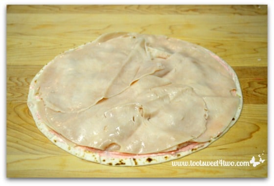 Thinly sliced deli turkey on strawberry cream cheese flour tortilla