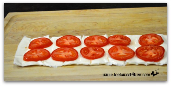 Sliced tomatoes on mozzarella log for Caprese Roll-ups