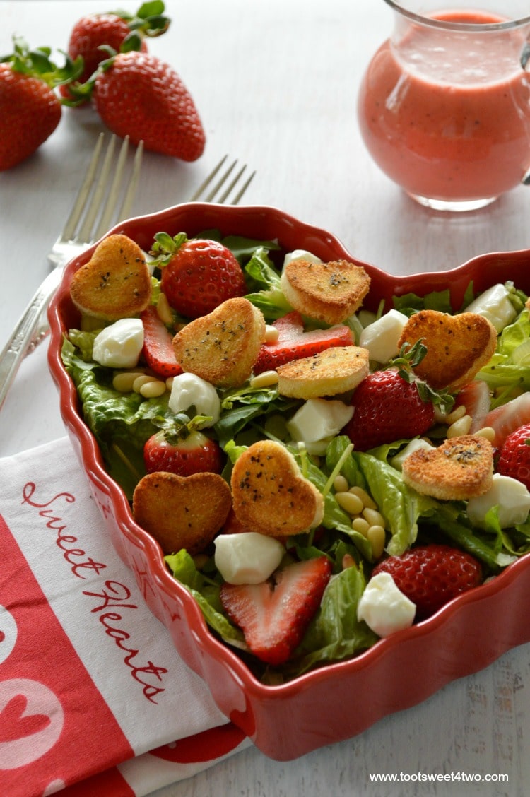 Green salad with strawberries in heart-shaped bowl with mini-heart croutons and pink dressing
