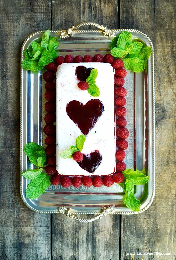 Looking for unique cheesecake recipes? Look no further! Sweetheart Raspberry Icebox Cheesecake is an easy, frozen, no bake dessert that combines an easy-to-make cheesecake layer with a layer of raspberry flavored ice cream and molded raspberry jam hearts. Frozen for hours or overnight, unmold this luscious concoction onto a pretty platter and then top with fresh raspberries and sprigs of mint. A spectacular-looking dessert, this delicious recipe with "wow" friends and family. | www.tootsweet4two.com