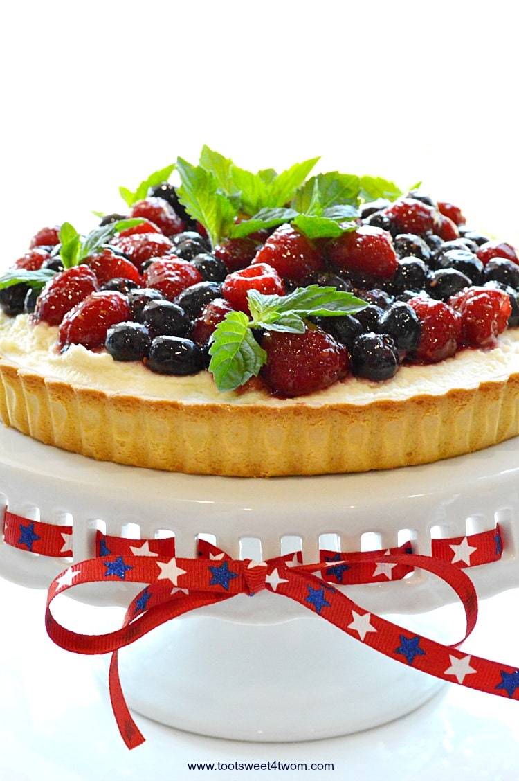 An easy, no-bake dessert, Patriotic Summer Berry Double-Cream Tart is a winning recipe to celebrate 4th of July or any other red, white and blue holiday. A flaky, store-bought sweet pastry tart shell covered with a sweet double-cream filling and topped with fresh fruit, makes a beautiful and delicious treat for Independence Day! | www.tootsweet4two.com